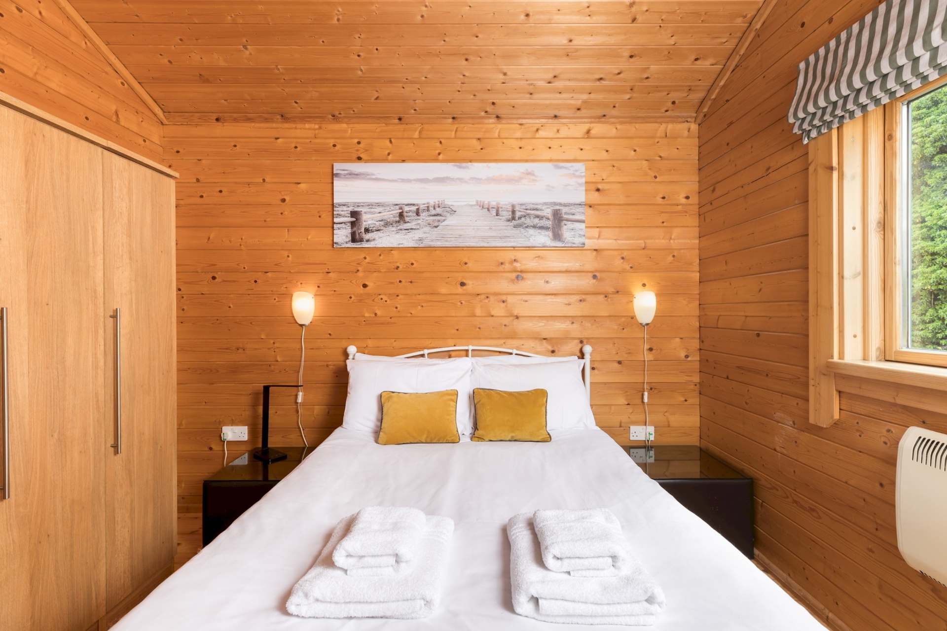 Main bedroom at Primrose Lodge with double bed, wall lights and mustard cushions