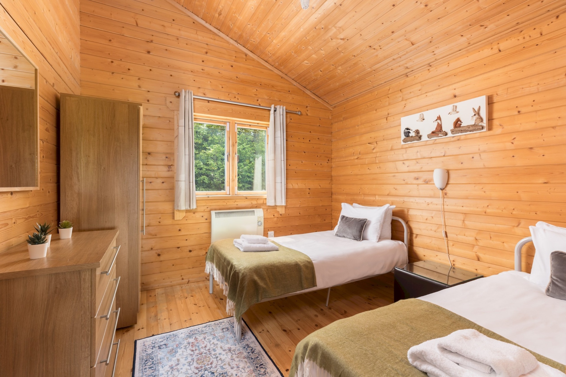 Twin bedroom at Primrose Lodge with chest of drawers and rug