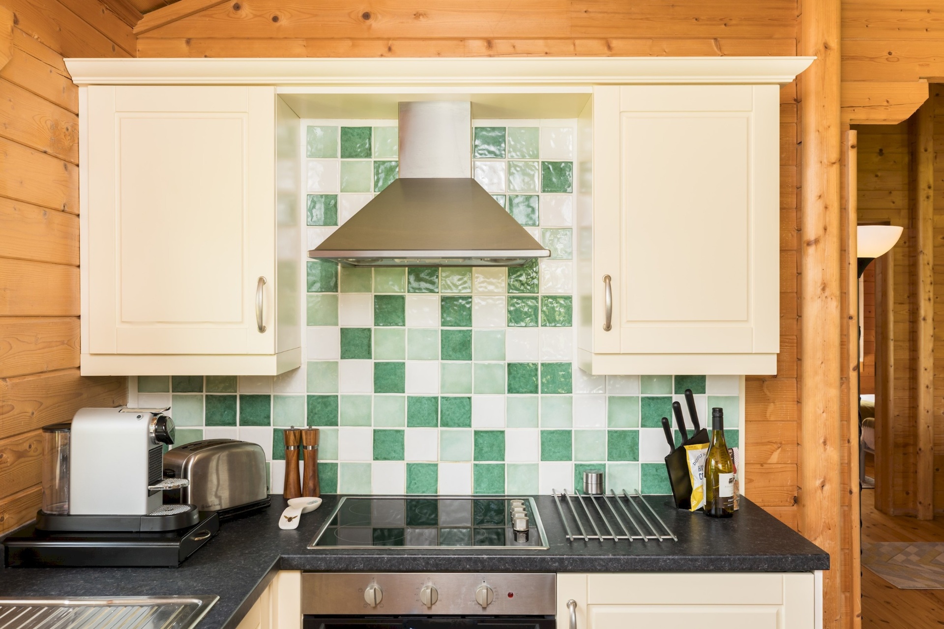 Kitchen at Primrose Lodge with green tiled splashback and extractor hood